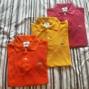 3 Lacoste men’s polo shirts.  Orange, golden, and maroon.